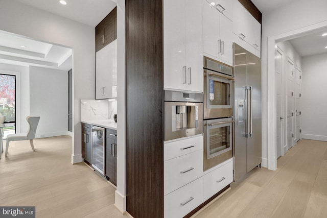 kitchen with appliances with stainless steel finishes, wine cooler, modern cabinets, white cabinetry, and recessed lighting