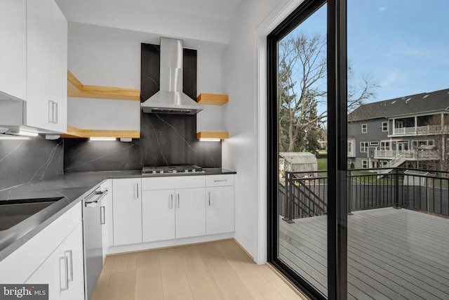kitchen with wall chimney exhaust hood, open shelves, appliances with stainless steel finishes, backsplash, and white cabinets