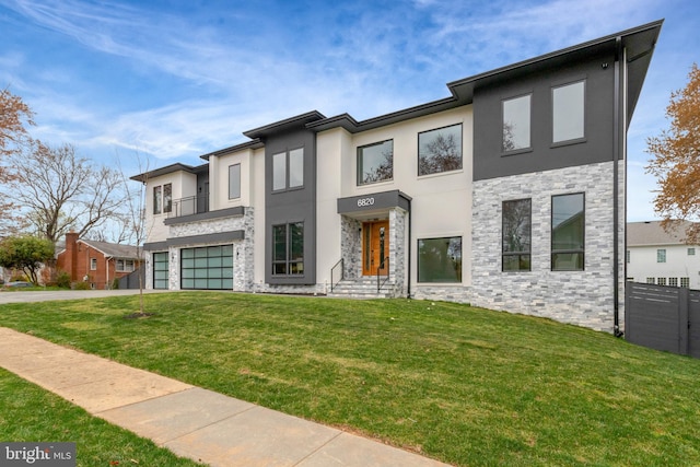 contemporary house with stone siding, stucco siding, a garage, and a front yard