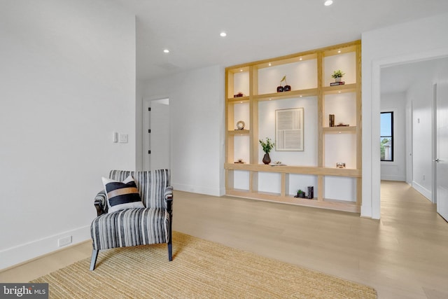 living area with wood finished floors, recessed lighting, baseboards, and built in shelves