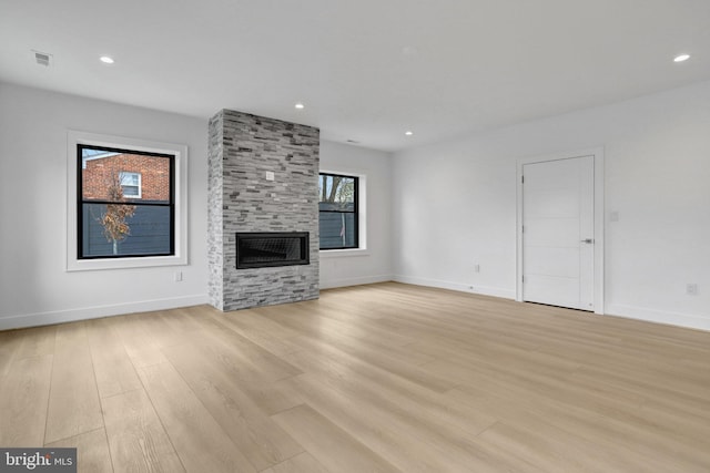 unfurnished living room featuring light wood-style flooring, a fireplace, baseboards, and recessed lighting