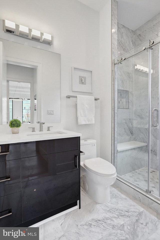 full bath with marble finish floors, toilet, vanity, and a stall shower