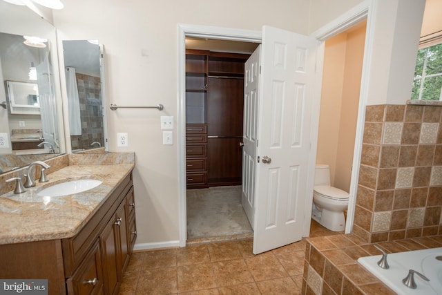 13076 Dove Tree Ct, Manassas, VA 20112 - bathroom with toilet, vanity, a relaxing tiled tub, and baseboards