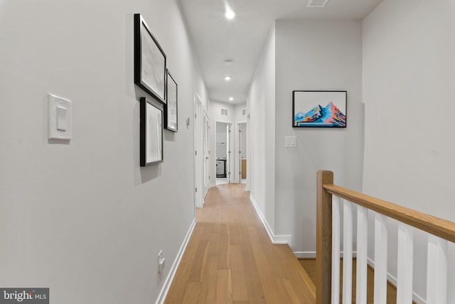 hallway with light wood-style flooring, recessed lighting, baseboards, and an upstairs landing