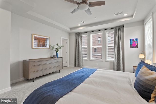 bedroom with a tray ceiling, light carpet, baseboards, and recessed lighting