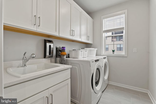 washroom featuring cabinet space, washing machine and dryer, and baseboards