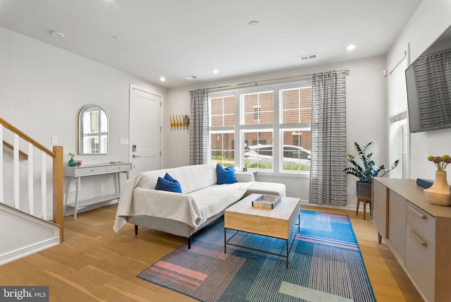 living area with light wood-style floors, stairs, and recessed lighting