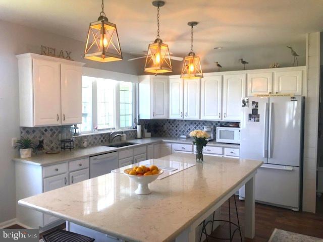 118 Riverview Dr, Dagsboro, DE 19939 - kitchen with white appliances, white cabinetry, tasteful backsplash, and a kitchen bar