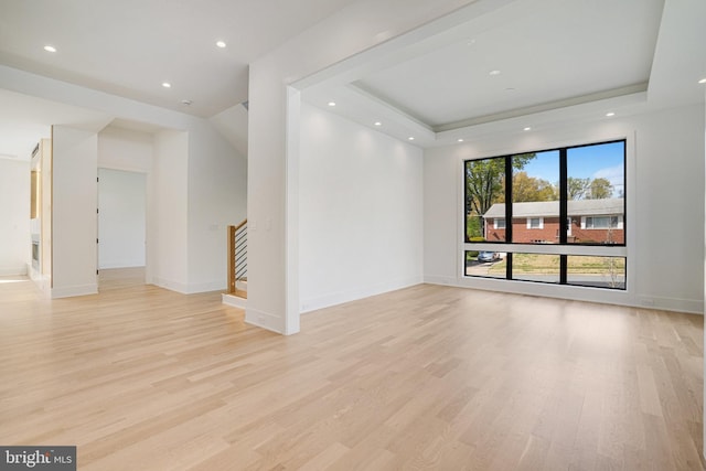 unfurnished room featuring light wood-style flooring, a raised ceiling, stairs, recessed lighting, and baseboards
