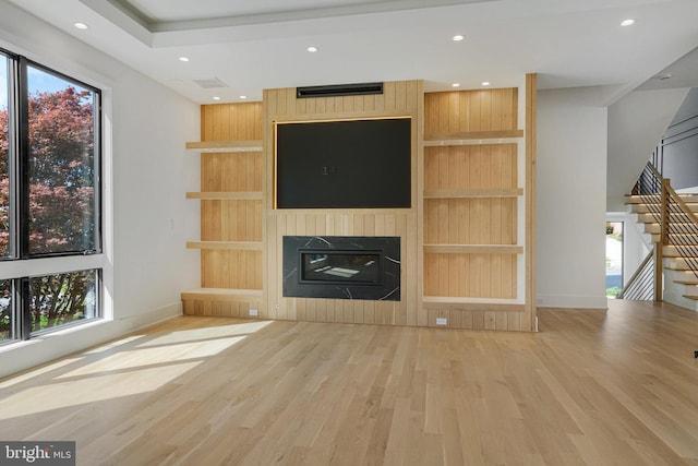unfurnished living room with wood finished floors, healthy amount of natural light, baseboards, a large fireplace, and recessed lighting