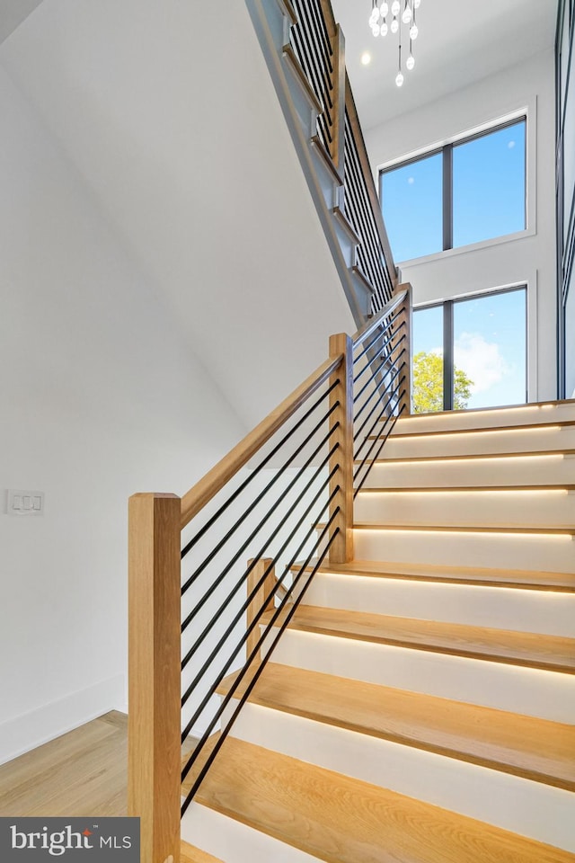 stairway with a chandelier, wood finished floors, baseboards, and recessed lighting
