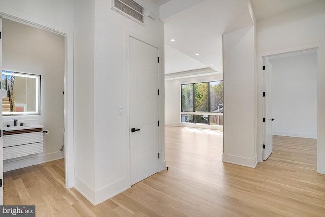 corridor with light wood finished floors, baseboards, and recessed lighting