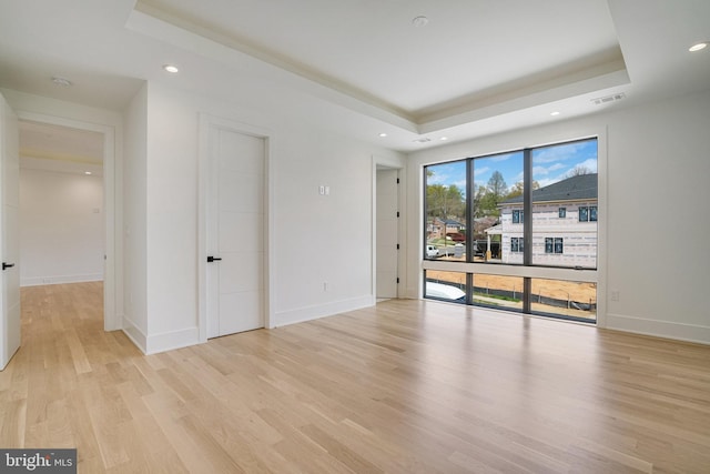 unfurnished room featuring a tray ceiling, light wood-type flooring, baseboards, and recessed lighting