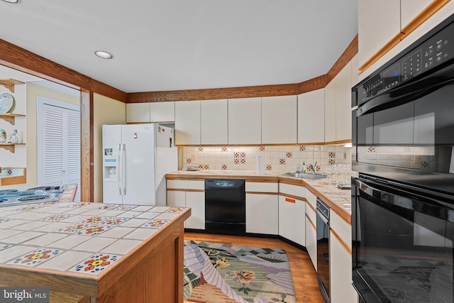 2 Fieldspring Ct, Lutherville Timonium, MD 21093 - kitchen with black appliances, tile countertops, light wood-style floors, white cabinets, and backsplash
