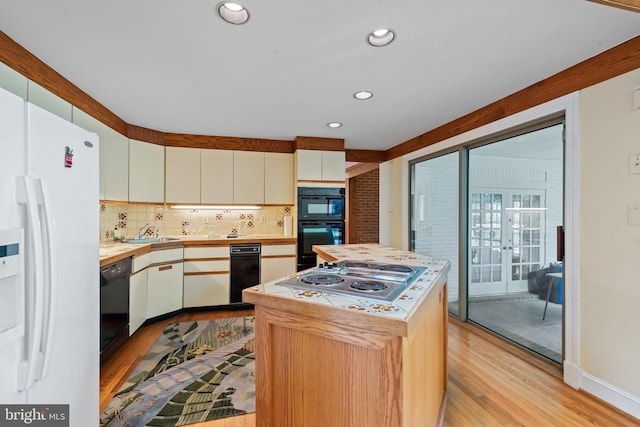 2 Fieldspring Ct, Lutherville Timonium, MD 21093 - kitchen featuring black appliances, light wood-style flooring, tasteful backsplash, a kitchen island, and white cabinetry