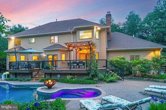 1016 Bellview Rd, Mclean, VA 22102 - back of property at dusk featuring a deck, a chimney, stairway, an outdoor pool, and a patio