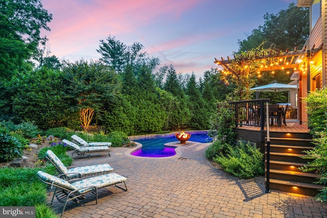 1016 Bellview Rd, Mclean, VA 22102 - pool at dusk featuring a wooden deck, an outdoor pool, a patio, and outdoor dining area