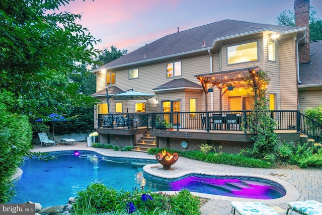 1016 Bellview Rd, Mclean, VA 22102 - back of property at dusk with a deck, a chimney, a patio, an outdoor pool, and an outdoor hot tub