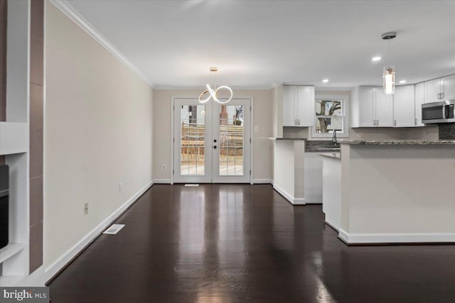 6867 Happyheart Ln, Columbia, MD 21045 - kitchen featuring stainless steel microwave, ornamental molding, white cabinets, dark wood-style flooring, and pendant lighting