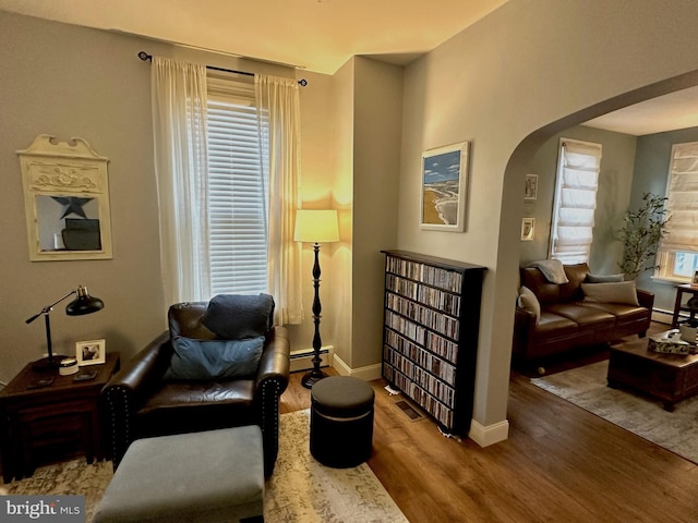 313 E Cherry St, Palmyra, PA 17078 - living area featuring arched walkways, wood finished floors, baseboards, and a baseboard heating unit