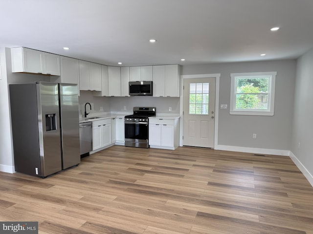 8110 Manson St, Landover, MD 20785 - kitchen with appliances with stainless steel finishes, light countertops, white cabinets, baseboards, and light wood-style flooring