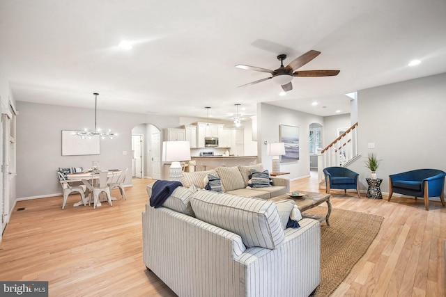 34637 Megan Ct, Lewes, DE 19958 - living room with arched walkways, stairway, a ceiling fan, light wood-style floors, and baseboards