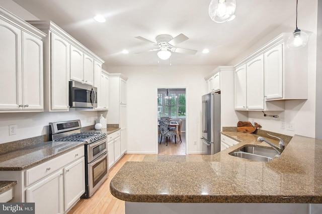34637 Megan Ct, Lewes, DE 19958 - kitchen with stainless steel appliances, a sink, light wood-style floors, ceiling fan, and dark stone counters