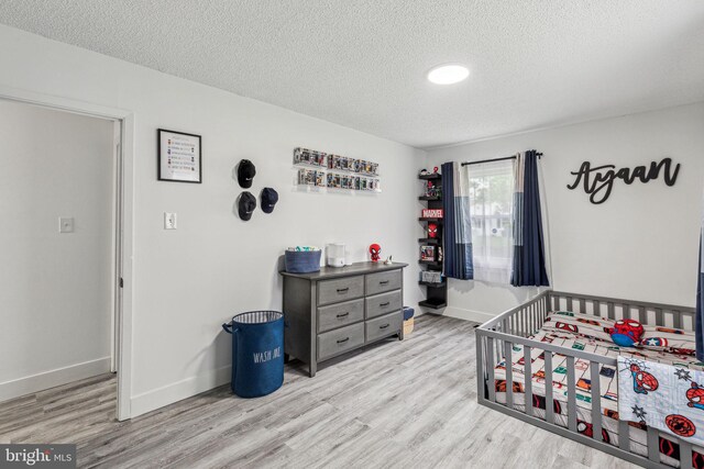 76 Torrington Ln, Willingboro, NJ 08046 - bedroom featuring a textured ceiling, wood finished floors, baseboards, and a crib