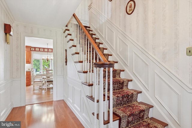 7 Taylor Ln, Doylestown, PA 18902 - stairs with a decorative wall, wood finished floors, a chandelier, wallpapered walls, and crown molding