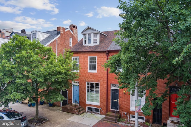 view of front of home featuring brick siding and a shingled roof
