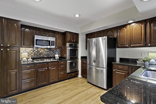 4714 Major Ct, Alexandria, VA 22312 - kitchen featuring appliances with stainless steel finishes, light wood-style floors, dark stone countertops, dark brown cabinetry, and backsplash