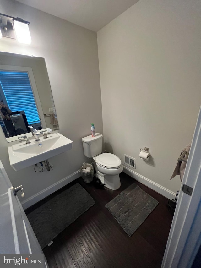 bathroom with toilet, wood finished floors, a sink, and baseboards