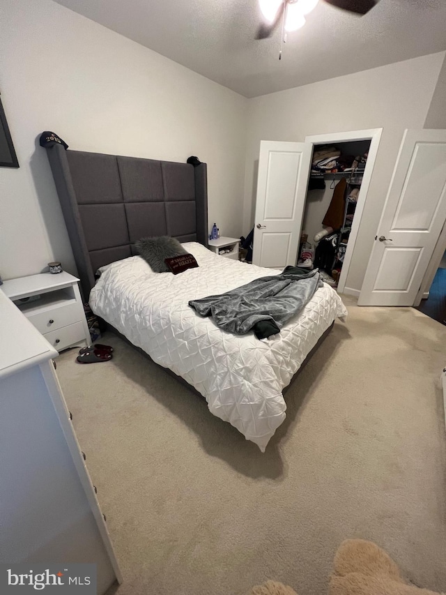 carpeted bedroom featuring a walk in closet, a closet, and ceiling fan