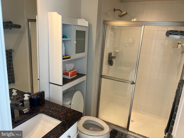 bathroom featuring a stall shower, toilet, and vanity