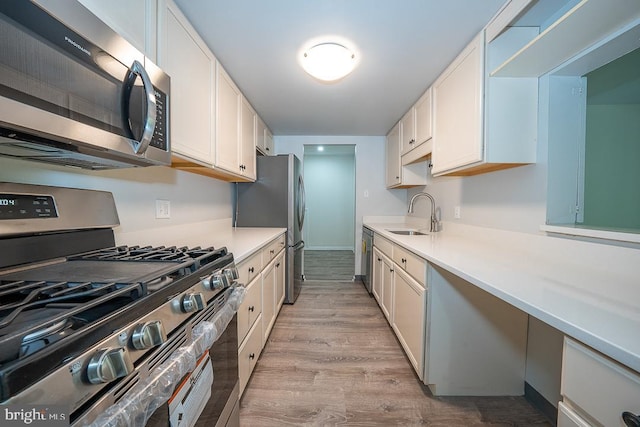 262 Drummers Ln Unit 262, Wayne, PA 19087 - kitchen with stainless steel appliances, a sink, light countertops, light wood-style flooring, and white cabinets