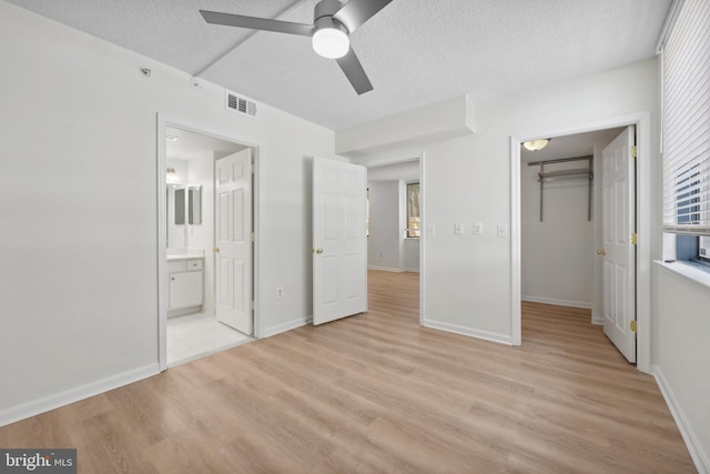 3830 9th St N Unit 110W, Arlington, VA 22203 - unfurnished bedroom featuring a textured ceiling, light wood-style floors, a closet, ensuite bath, and a spacious closet