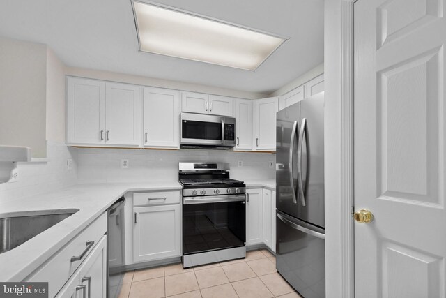 3830 9th St N Unit 110W, Arlington, VA 22203 - kitchen featuring stainless steel appliances, white cabinets, decorative backsplash, light tile patterned floors, and light stone countertops