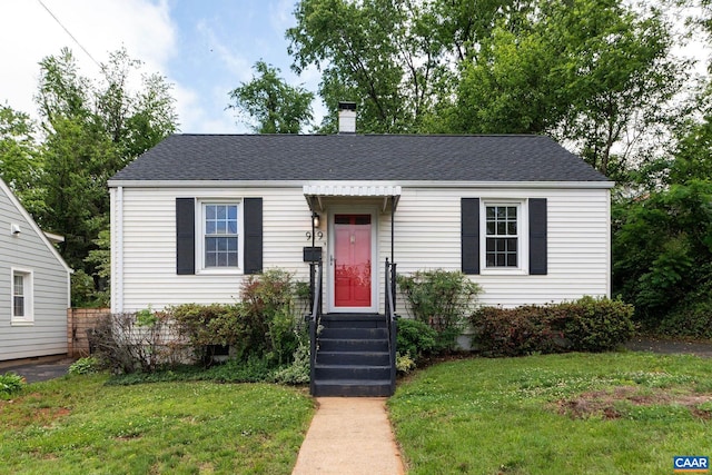 view of front of property featuring a front lawn, a chimney, and roof with shingles