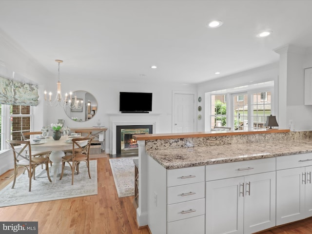 7287 Evans Mill Rd, Mclean, VA 22101 - kitchen featuring white cabinets, light stone countertops, a glass covered fireplace, a peninsula, and recessed lighting