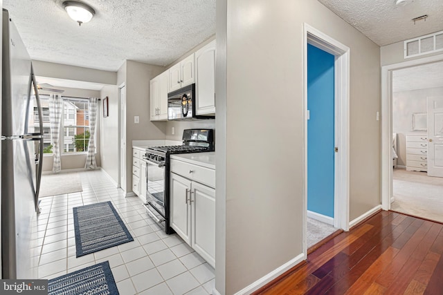 8357 Cypress Mill Rd Unit 8357, Nottingham, MD 21236 - kitchen featuring stainless steel appliances, a textured ceiling, white cabinetry, light wood-style flooring, and baseboards