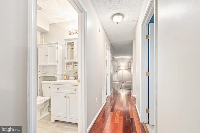 8357 Cypress Mill Rd Unit 8357, Nottingham, MD 21236 - corridor featuring a textured ceiling, wood finished floors, a sink, and baseboards