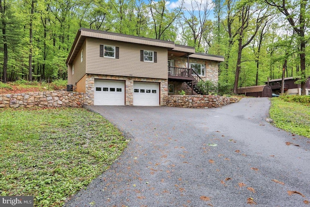 view of front of house with stone siding, stairway, driveway, and a garage