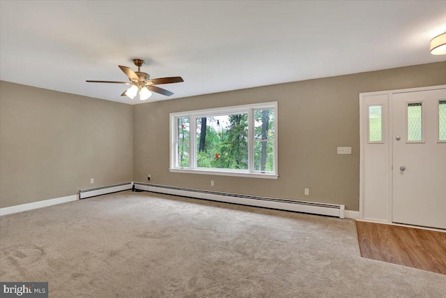 carpeted foyer entrance with ceiling fan, a baseboard heating unit, and baseboards