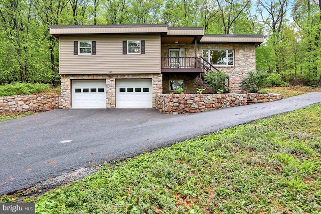 view of front facade featuring stone siding, driveway, a garage, and stairway
