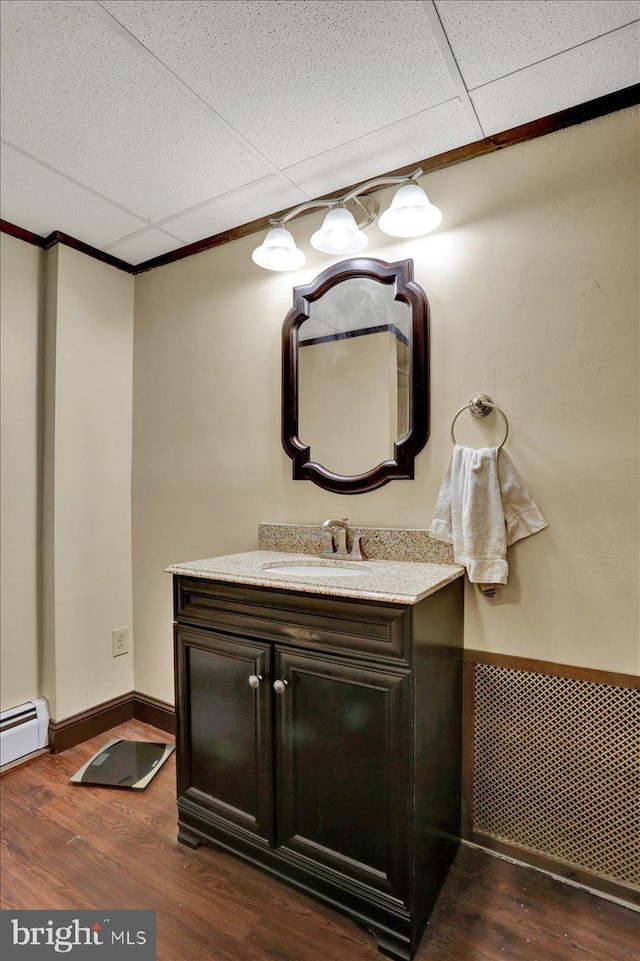 bathroom featuring wood finished floors, a baseboard heating unit, vanity, and ornamental molding