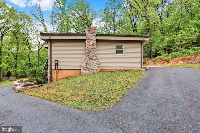 view of property exterior with a chimney and driveway