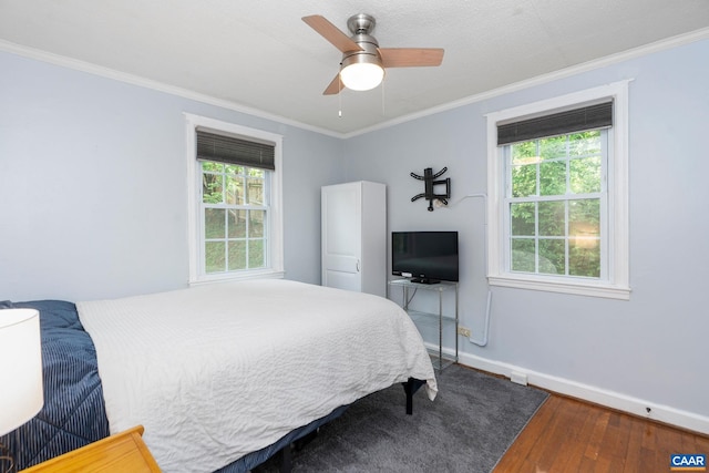 bedroom featuring multiple windows, hardwood / wood-style flooring, baseboards, crown molding, and ceiling fan