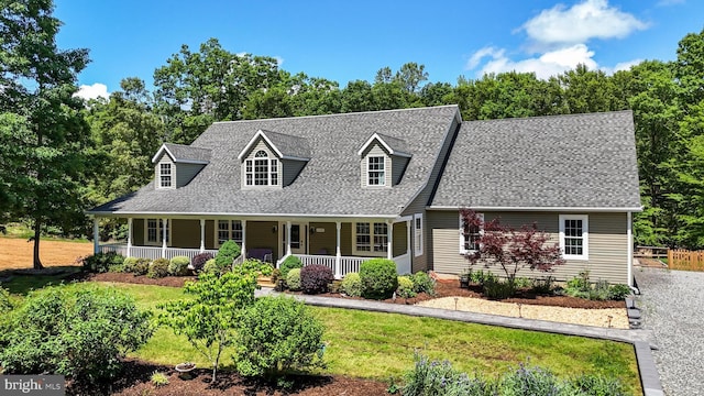 cape cod home with a shingled roof, covered porch, and a front lawn
