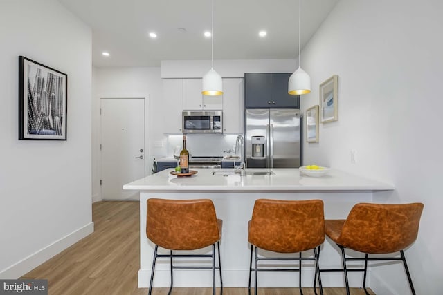 2310 4th St NE Unit 22, Washington, DC 20002 - kitchen featuring stainless steel appliances, a breakfast bar, a peninsula, light wood finished floors, and decorative light fixtures