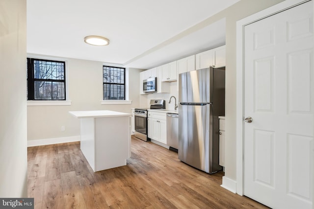 212 Oakwood St SE Unit B5, Washington, DC 20032 - kitchen with appliances with stainless steel finishes, a kitchen island, white cabinets, light countertops, and light wood-type flooring